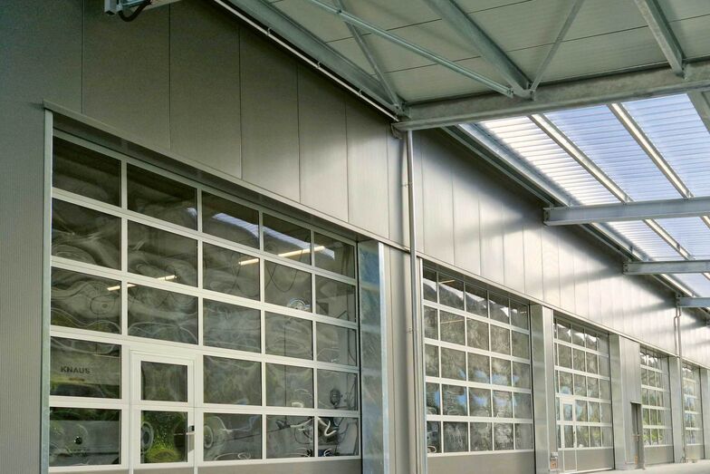 Des deux côtés du bâtiment se trouvent de grandes portes d’accès vers les places de l’atelier.