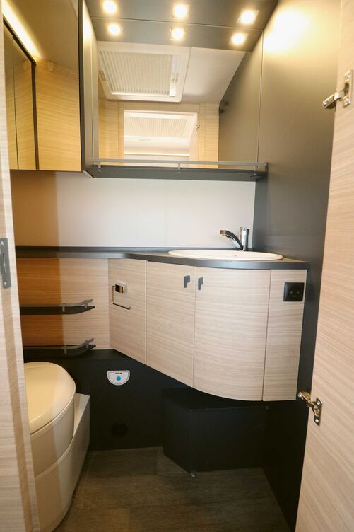 La salle de bains claire dotée de grands miroirs abrite tout l’essentiel, mais le bac de douche a été volontairement supprimé pour permettre un accès sans marche.