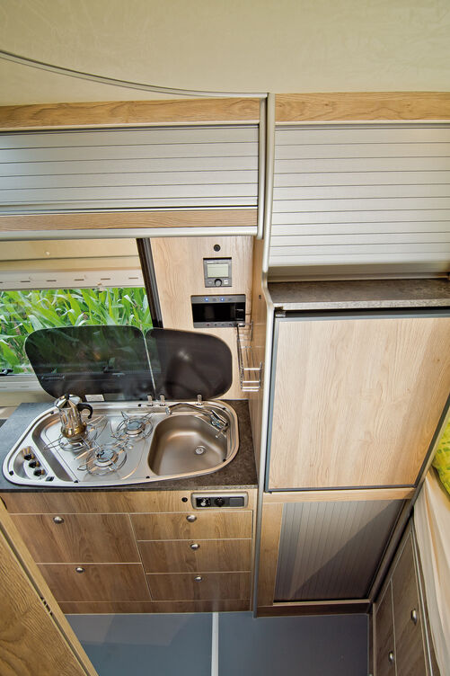 Hochgesetzter Kühlschrank neben der Spüle.