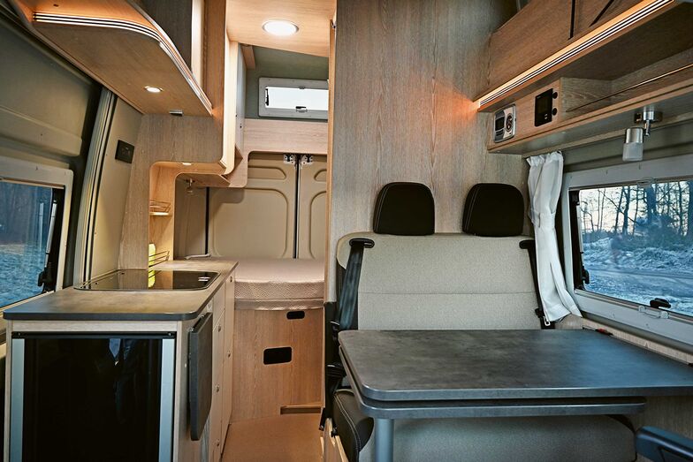 Vue depuis la cabine sur la demi-dînette et le long bloc cuisine, jusqu’au lit double arrière.