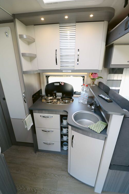 Die komplett ausgestattete Küche mit dem Thekenaufsatz, Dreiflammherd, tiefe Rundspüle, Handtuchhalter, offene Ablagen sowie reichlich Stauraum lässt nichts vermissen.