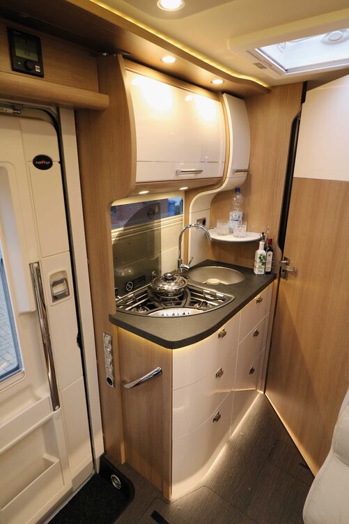 L’élégante cuisine dotée de façades claires et brillantes et de nombreux éléments d’éclairage séduit par sa fonctionnalité.