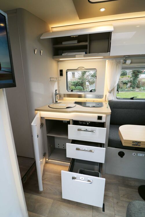 La cuisine compacte avec façades claires brillantes, plan de travail effet bois et nombreux éclairages séduit tout autant que son équipement.