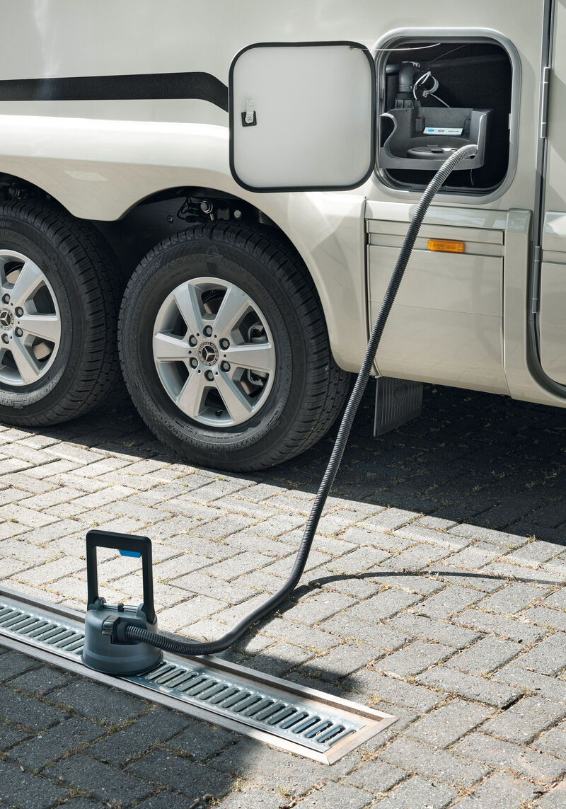 Der Stutzen mit Handgriff am Ende des Schlauchs wird auf dem Gitter der Auslassstelle platziert.