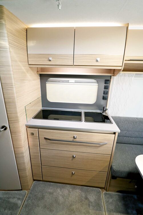 Auch optisch gefällt die kompakte Küche mit hoher Funktionalität und gut gemachter Fenstereinfassung mit Plissee-Rollo und den zentral eingebauten Bedienungselementen.